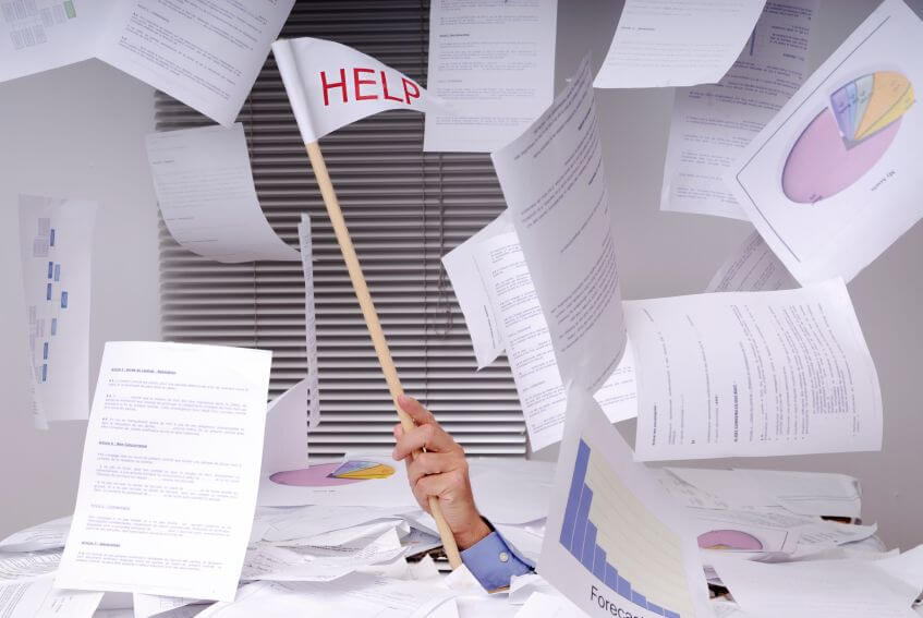 Flooded with work, Help sign amidst scattered documents and charts representing application failure.